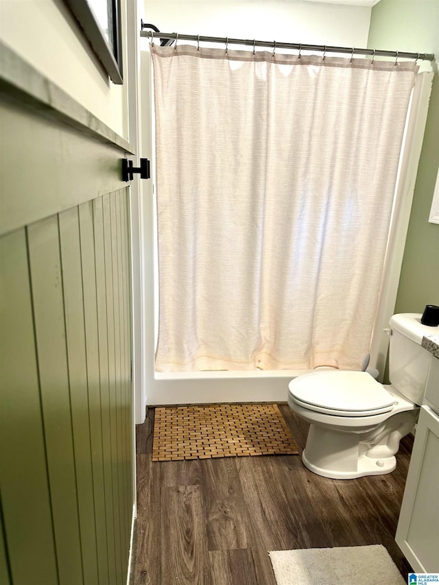 bathroom with toilet, a shower with shower curtain, and wood finished floors