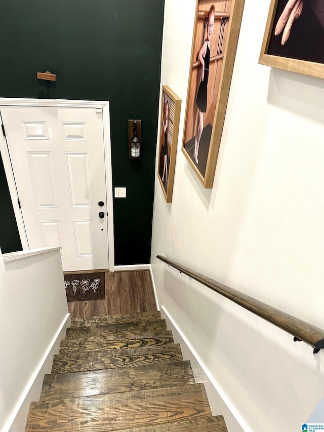 staircase featuring wood finished floors and baseboards