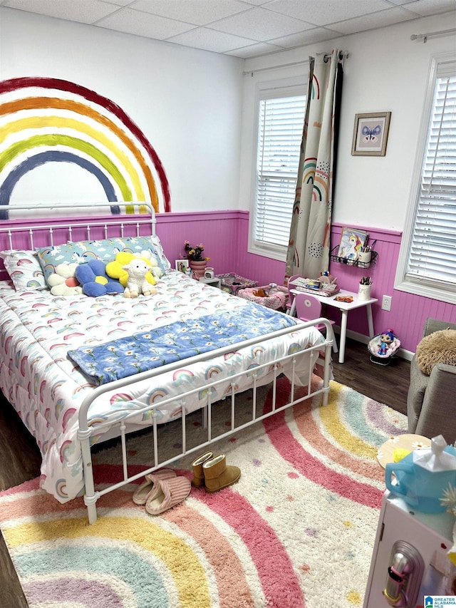 bedroom featuring a paneled ceiling, multiple windows, and wainscoting