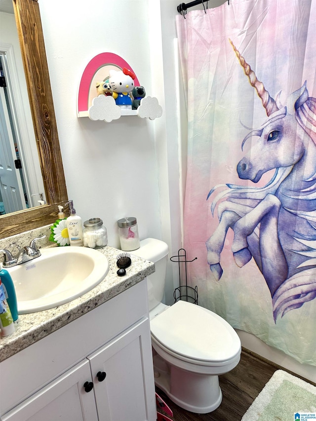 bathroom with toilet, wood finished floors, and vanity