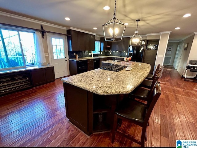 kitchen featuring dark wood-type flooring, a kitchen island, decorative backsplash, and black appliances