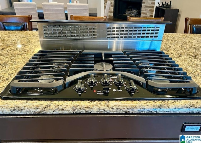 interior details with black gas stovetop, light stone counters, and decorative backsplash