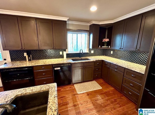 kitchen with black appliances, light wood-type flooring, a sink, and decorative backsplash