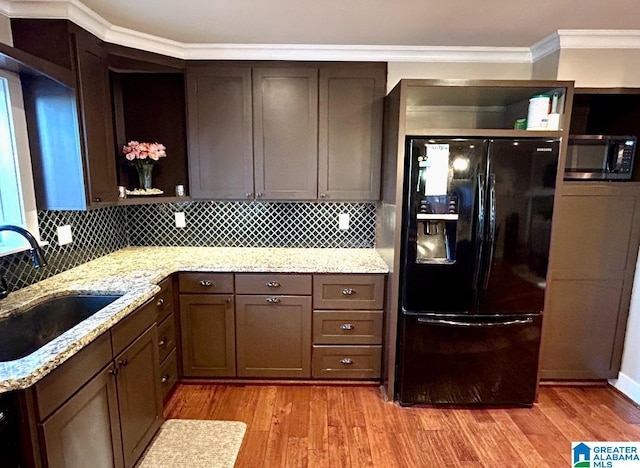 kitchen with a sink, stainless steel microwave, open shelves, and black fridge