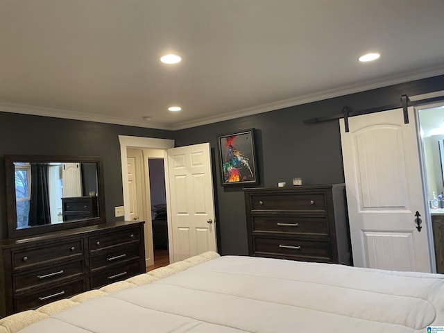 bedroom with a barn door, recessed lighting, wood finished floors, and crown molding