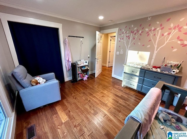 bedroom with ornamental molding, visible vents, baseboards, and wood finished floors