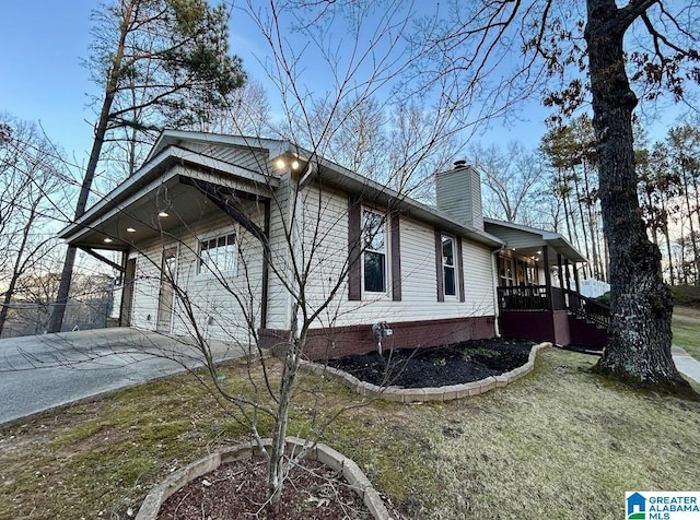 view of side of property featuring a garage, driveway, a porch, and a chimney