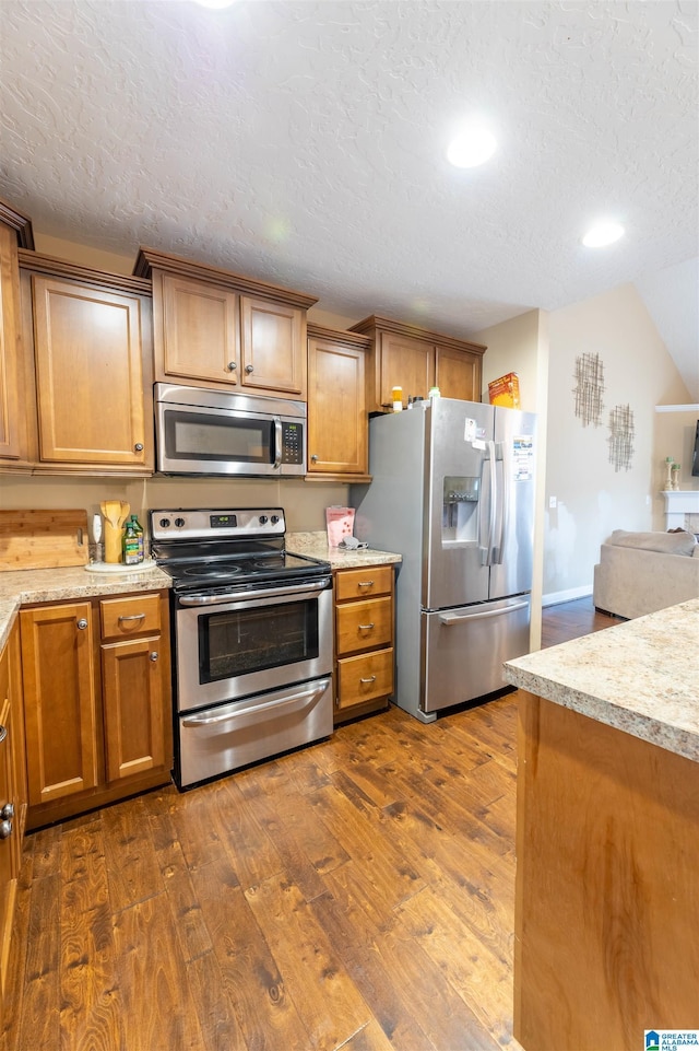 kitchen featuring stainless steel appliances, dark wood-style flooring, and brown cabinets