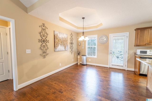 unfurnished dining area with dark wood-type flooring, a tray ceiling, and baseboards