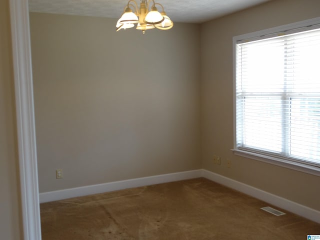 unfurnished room with baseboards, visible vents, a chandelier, and carpet flooring