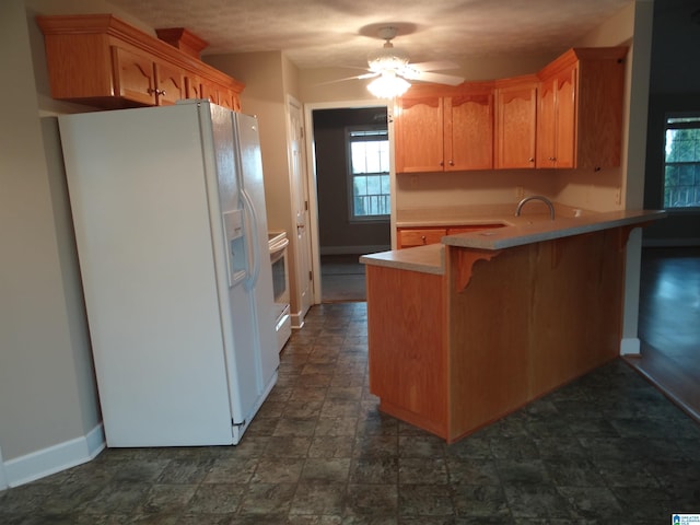 kitchen with white appliances, baseboards, a breakfast bar area, a peninsula, and light countertops