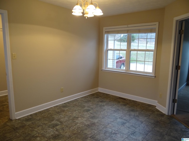 spare room featuring an inviting chandelier, visible vents, baseboards, and stone finish flooring