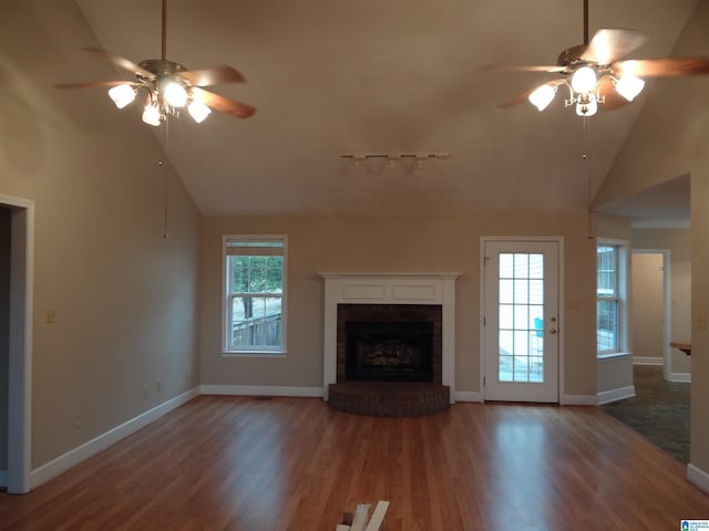 unfurnished living room with a brick fireplace, ceiling fan, baseboards, and wood finished floors