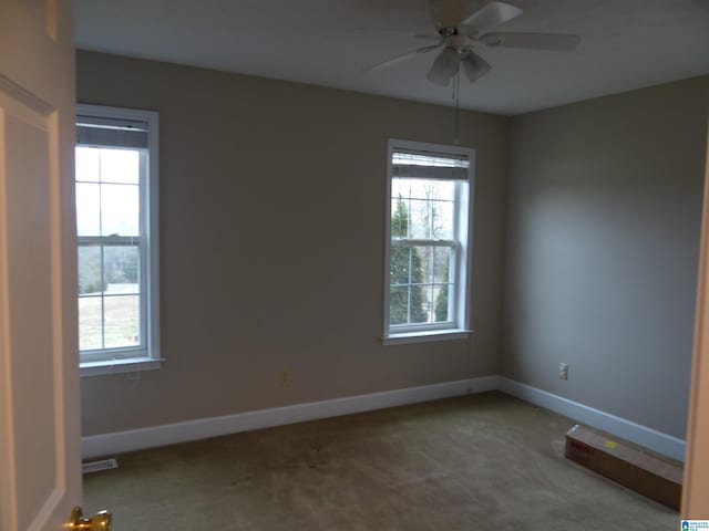 carpeted spare room featuring visible vents, baseboards, and ceiling fan