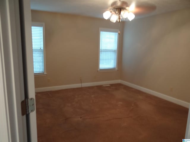 carpeted empty room featuring a wealth of natural light, ceiling fan, and baseboards