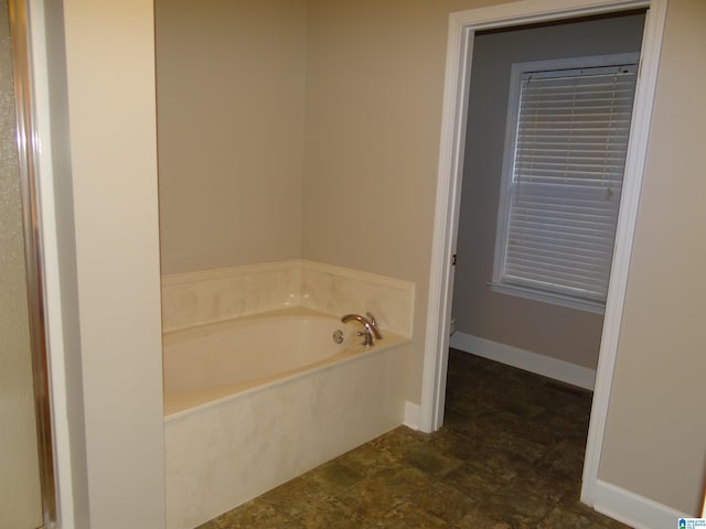 full bath with a bath and baseboards