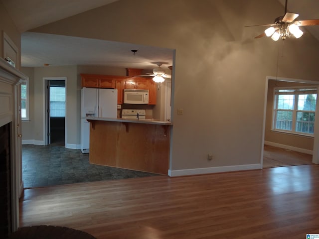 kitchen featuring white appliances, a ceiling fan, wood finished floors, a peninsula, and a fireplace