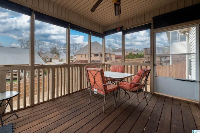 sunroom featuring a ceiling fan and a residential view