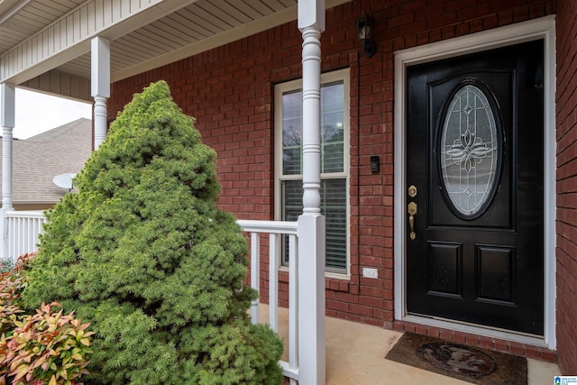 property entrance with covered porch and brick siding