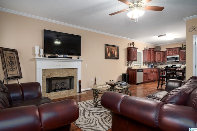 living room with dark wood finished floors, a premium fireplace, ornamental molding, a ceiling fan, and baseboards