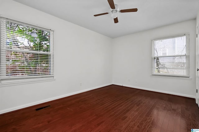 spare room featuring a ceiling fan, visible vents, baseboards, and hardwood / wood-style flooring