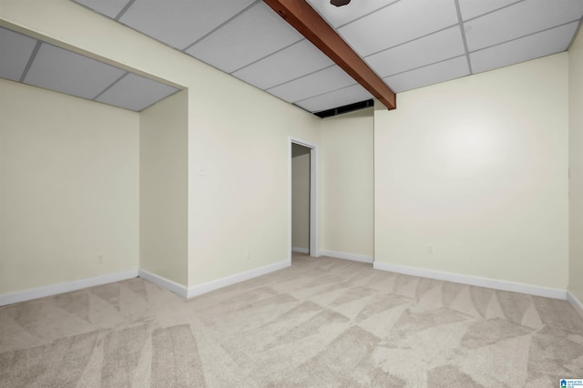 empty room with carpet floors, beamed ceiling, a paneled ceiling, and baseboards