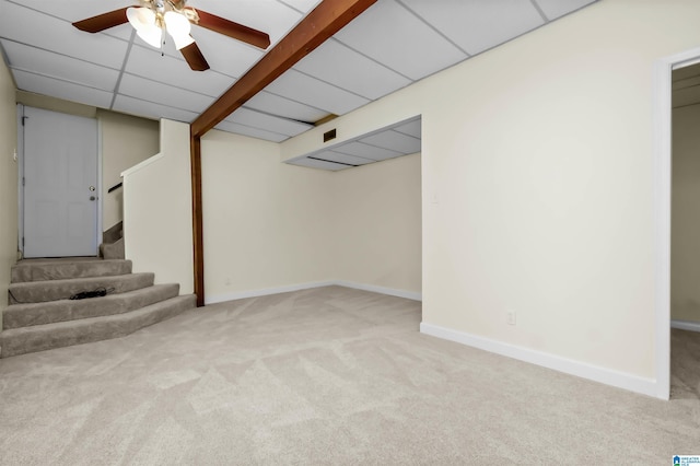 finished basement featuring baseboards, a drop ceiling, ceiling fan, stairway, and carpet