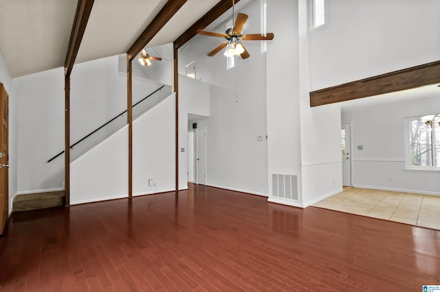 unfurnished living room featuring visible vents, ceiling fan, wood finished floors, high vaulted ceiling, and beam ceiling