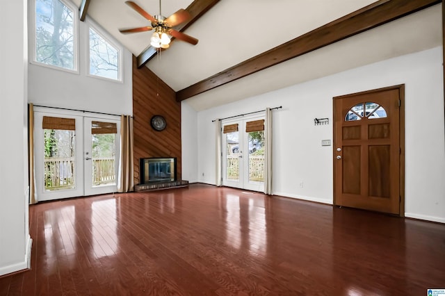 unfurnished living room with french doors, beam ceiling, a fireplace, wood finished floors, and high vaulted ceiling