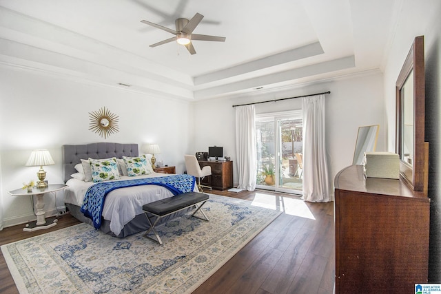 bedroom featuring ceiling fan, dark wood finished floors, baseboards, access to exterior, and a raised ceiling