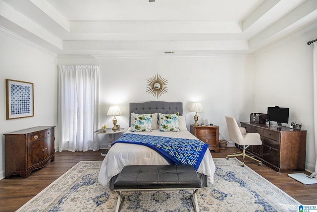 bedroom with a tray ceiling, visible vents, dark wood finished floors, and baseboards