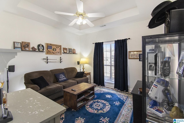 living room featuring a ceiling fan, a raised ceiling, and visible vents