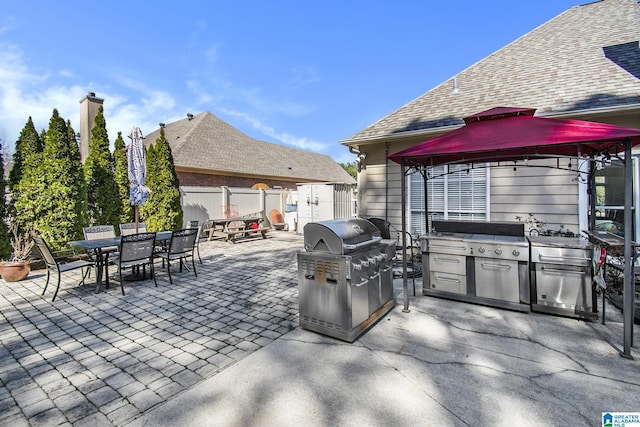 view of patio / terrace featuring fence, a grill, a gazebo, exterior kitchen, and outdoor dining space