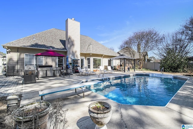 view of swimming pool featuring area for grilling, fence, a gazebo, a fenced in pool, and a patio area