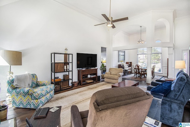 living room with a ceiling fan, crown molding, a high ceiling, and wood finished floors