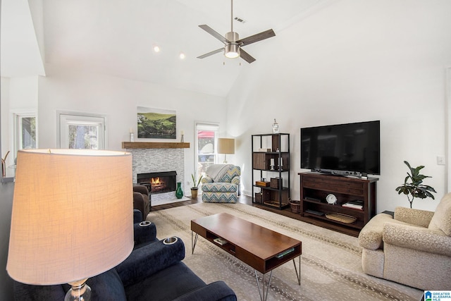 living area with visible vents, a fireplace with flush hearth, ceiling fan, wood finished floors, and high vaulted ceiling