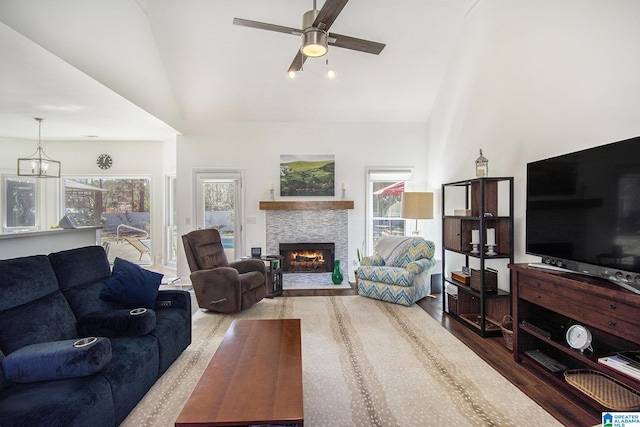 living room with a lit fireplace, high vaulted ceiling, ceiling fan, and wood finished floors