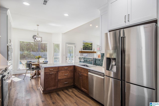 kitchen featuring a peninsula, a sink, visible vents, light countertops, and appliances with stainless steel finishes