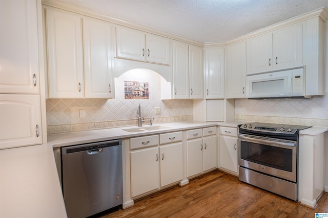 kitchen with light countertops, decorative backsplash, appliances with stainless steel finishes, a sink, and wood finished floors