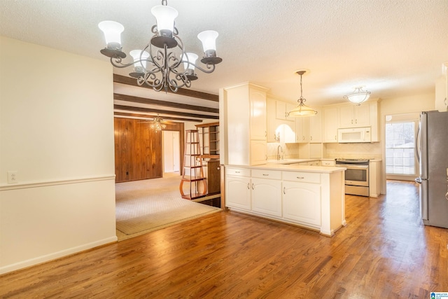 kitchen featuring light wood finished floors, appliances with stainless steel finishes, a textured ceiling, and beam ceiling