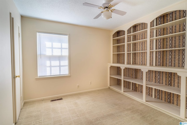 carpeted empty room featuring visible vents, ceiling fan, a textured ceiling, and baseboards