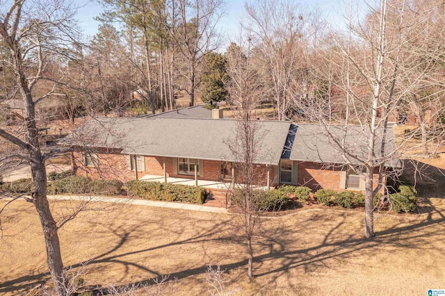 ranch-style house featuring a shingled roof and brick siding