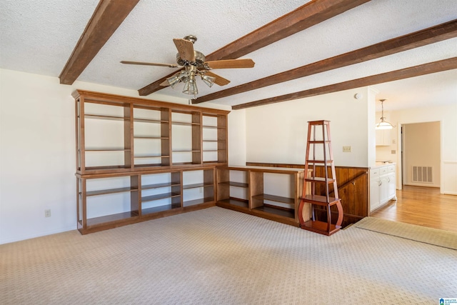 spare room featuring carpet floors, visible vents, a ceiling fan, a textured ceiling, and beamed ceiling