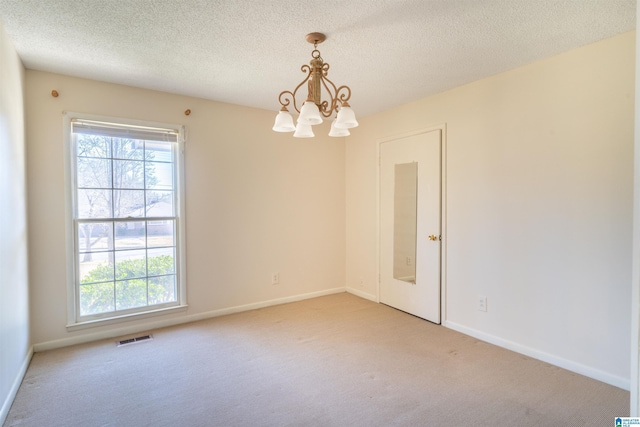 unfurnished room featuring a chandelier, a healthy amount of sunlight, a textured ceiling, and light colored carpet