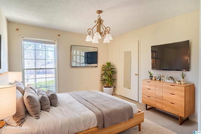 bedroom with a textured ceiling, a chandelier, and light colored carpet