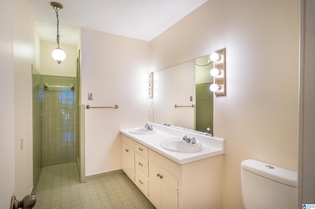 bathroom with toilet, a tile shower, and a sink