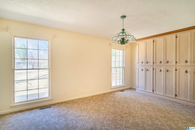 empty room with a textured ceiling, baseboards, visible vents, and light colored carpet