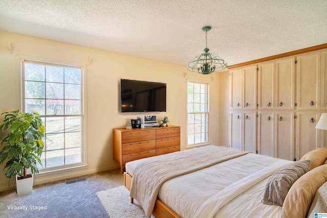 bedroom featuring a textured ceiling, carpet floors, multiple windows, and visible vents