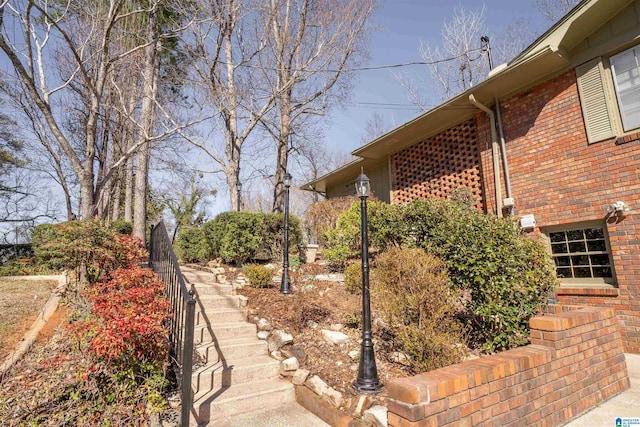 view of property exterior featuring brick siding and stairway