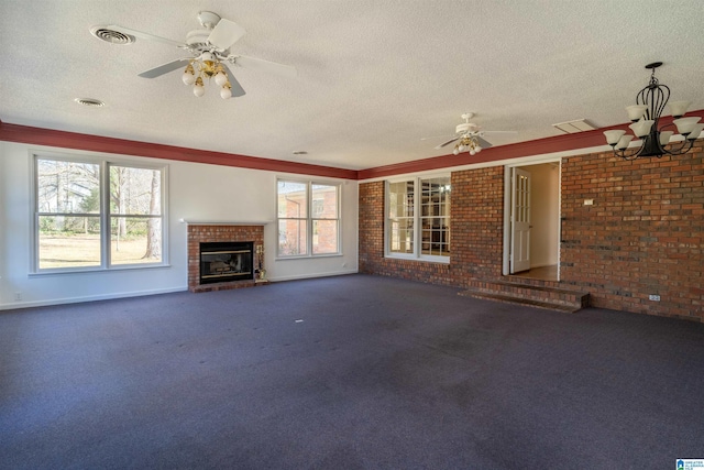 unfurnished living room featuring a healthy amount of sunlight, brick wall, visible vents, and a textured ceiling